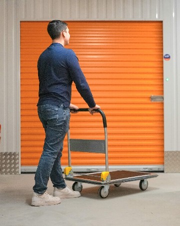 Client utilisant un chariot de manutention chez MondialBox Gen&egrave;ve, illustrant un service de self-stockage pratique, accessible et adapt&eacute; aux particuliers comme aux professionnels.